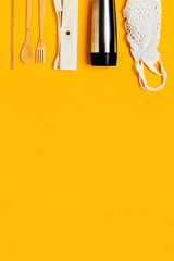 A group of eco friendly kitchen accessories. Thermo mug, bamboo cutlery, reusable drinking tube on yellow background.