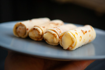twisted pancakes stuffed with straw on a dark plate