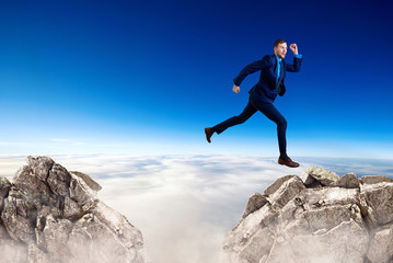 Fototapeta na wymiar Businessman jumping through the gap among mountains.