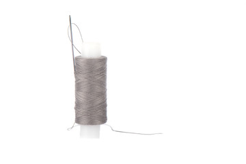 Close-up photo of a spool with gray thread and a needle isolated over white background.