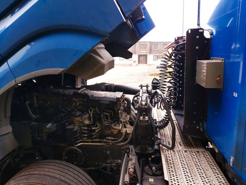 Space Between Truck Cab And Trailer. Folded Tractor Connected With Hoses And Connections.Tilted Blue  Cab Tractor And Attached Blue Trailer. A Revision Or Repair Is Required.