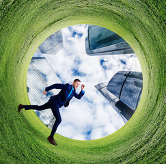 Young businessman running into green field circle.