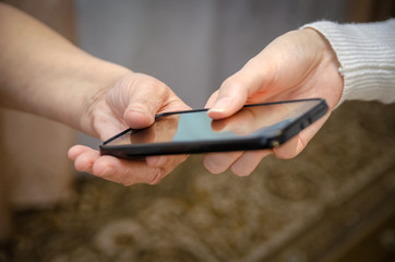 hand of a young girl passes a mobile phone to the hand of an elderly woman