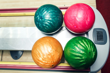 multi-colored bowling balls lie on shelf in bowling club