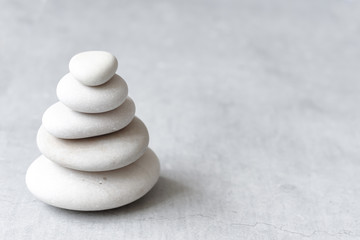 Fototapeta na wymiar Stack of white pebbles on a neutral light grey background as balance and wellness concept