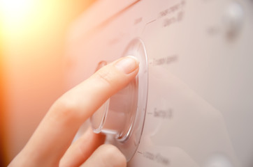 woman's hand adjusts the settings on the washing machine's control panel using a wheel. Photo with...