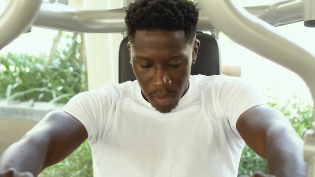 African American athlete doing exercise for chest muscles on pec deck machine during workout in gym.