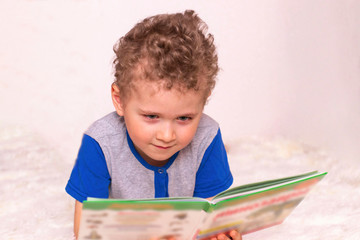 Little boy is reading a book. Children's Book Day, an introduction to reading. Lovely child reading...
