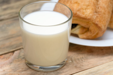 Glass of milk, rolls, sliced loaf on a wooden background