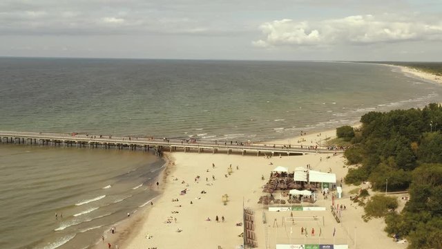 PALANGA, LITHUANIA - JULY, 2019: Aerial view of famous pier of Palanga, sand beach, waves and green pine tree forest.