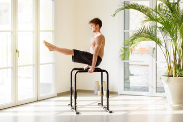 Fototapeta premium Fit young man working out on parallel bars