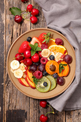 Obraz na płótnie Canvas bowl of mixed fruits- berry, cherry, apricot, kiwi, strawberry, banana- healthy dessert