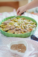 Little boy helps cooking tart with fresh plums