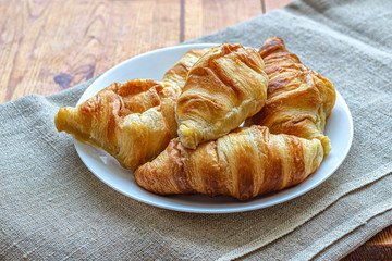 White plate with fresh French mini croissants on canvas