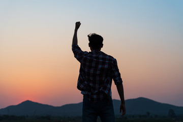Man with fist in the air during sunset sunrise mountain in background. Stand strong. Feeling...