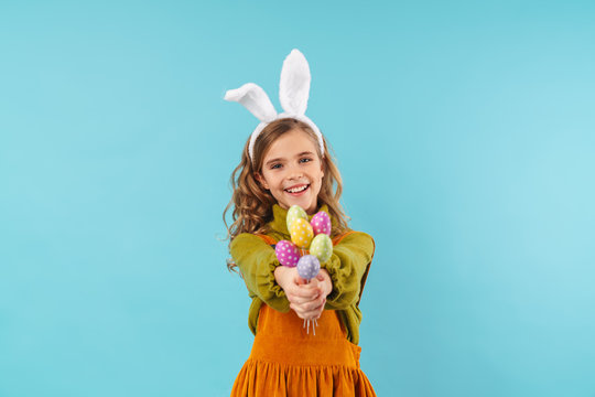 Photo of joyful blonde girl smiling and holding colorful eggs