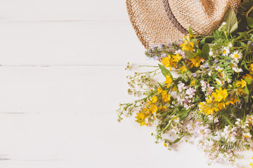 wild flowers with straw hat on white background. Top view, flat lay. copy space