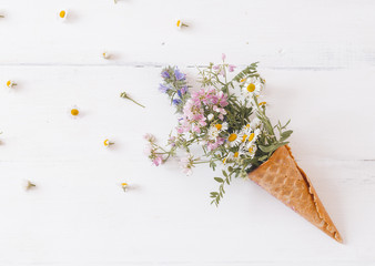 waffle cone with a wild flowers on a white background. Creative design. Top view, flat lay.