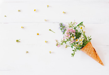 waffle cone with a wild flowers on a white background. Creative design. Top view, flat lay.