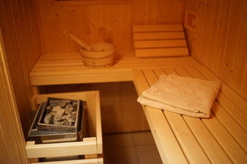 Inside a small wooden house sauna with heated rocks and bucke
