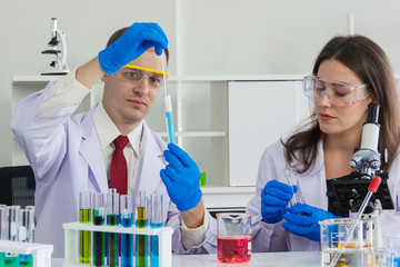 female and male scientist ware safety glasses are doing dip chemical to beaker in laboratory