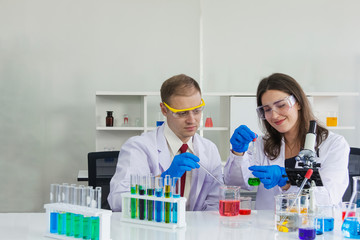 female and male scientist ware safety glasses are doing dip chemical to beaker in laboratory