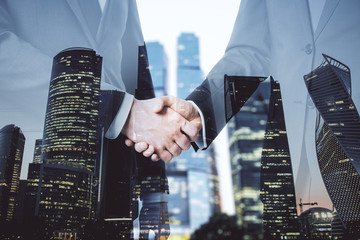 Businesspeople shaking hand on abstract skyscraper background.