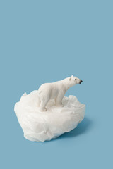 White polar bear on plastic bag on blue background, plastic pollution and climate change concept