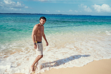 Fototapeta na wymiar Tropical vacation. Young man enjoying the view of beautiful white sand sea beach.
