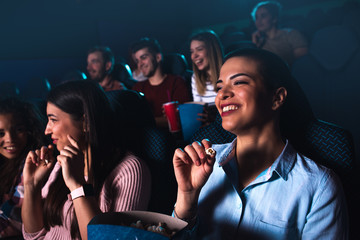 Group of cheerful people laughing while watching movie in cinema.