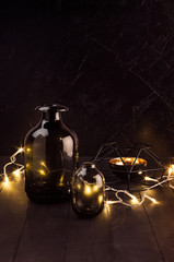 Luxury home interior in black and gold color - shimmer warm lights with black bottles, abstract sculpture on dark wood table, plaster wall, vertical.