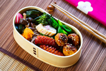 Japanese bento box with meatballs, sausage and vegetables