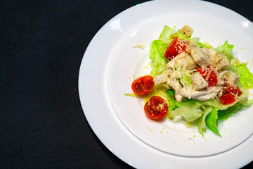 white plate with salad on a black table. freespace