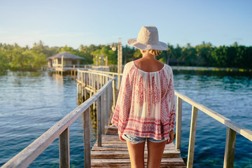 Vacation on tropical island.  Back view of young woman in hat enjoying sea view from wooden bridge terrace, Siargao Philippines