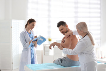 Female orthopedist examining patient's arm in clinic