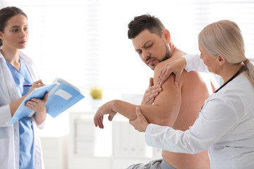 Obraz premium Female orthopedist examining patient's arm in clinic