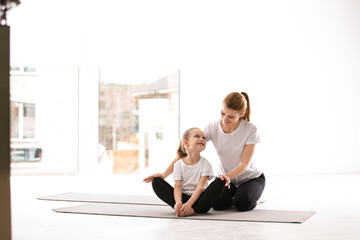 Obraz premium Mother and daughter in matching sportswear doing yoga together at home