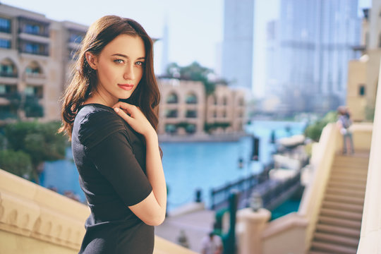Close-up portrait of beautiful caucasian woman with charming smile and long hair walking on the city streets.
