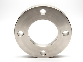 Flat stainless steel flange on a light background.