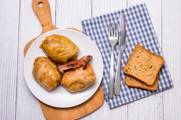 Cabbage rolls with meat, rice and vegetables in a white plate on a wooden table. Stuffed cabbage leaves with meat. Sarma, dolma, Chou farci, golubtsy or golabki.