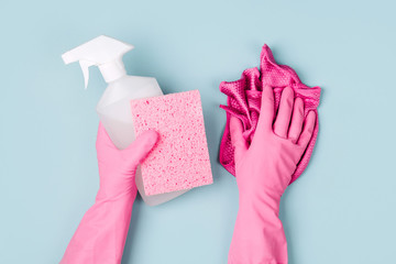 Hands in pink gloves hold detergents. Cleaning or housekeeping concept background. Copy space. Flat...