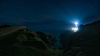 Beams of light shining from Fanad Head Lighthouse at dark night with sky full of stars. Long...