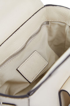 Look inside an open, elegant women's bag made of white leather with a clean place for your brand, isolated on a white background with shadows.
