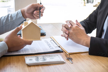 Real estate agent are presenting home loan and giving house, keys to customer after signing contract to buy house with approved property application form