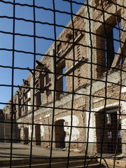 Ruins of a building with empty windows behind an iron fence