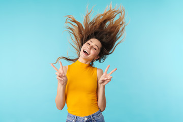 Portrait of excited woman smiling and gesturing peace sign with fingers