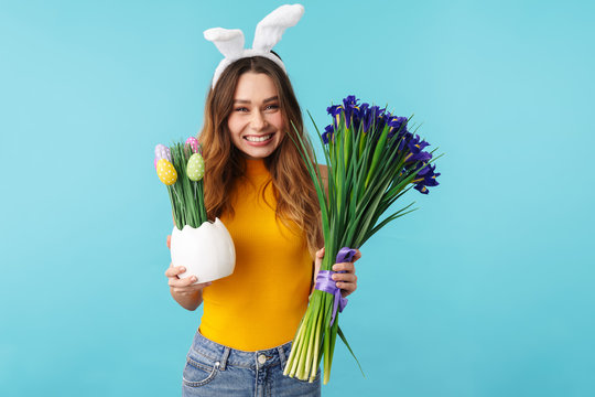 Portrait Of Young Woman Wearing Bunny Ears Holding Easter Eggs And Flowers