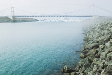 Road bridge in glacier blue lagoon Jokulsarlon on Skaftafell glacier in Iceland. Foggy winter weather.
