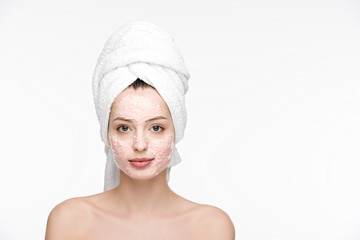 attractive girl with peeling mask on face and towel on head looking at camera isolated on white