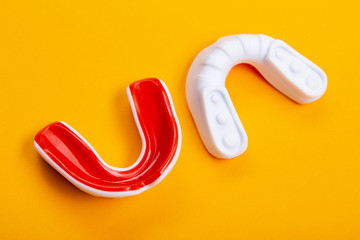 two boxing mouthguards, red and white, lie on a yellow background, concept, diagonal arrangement